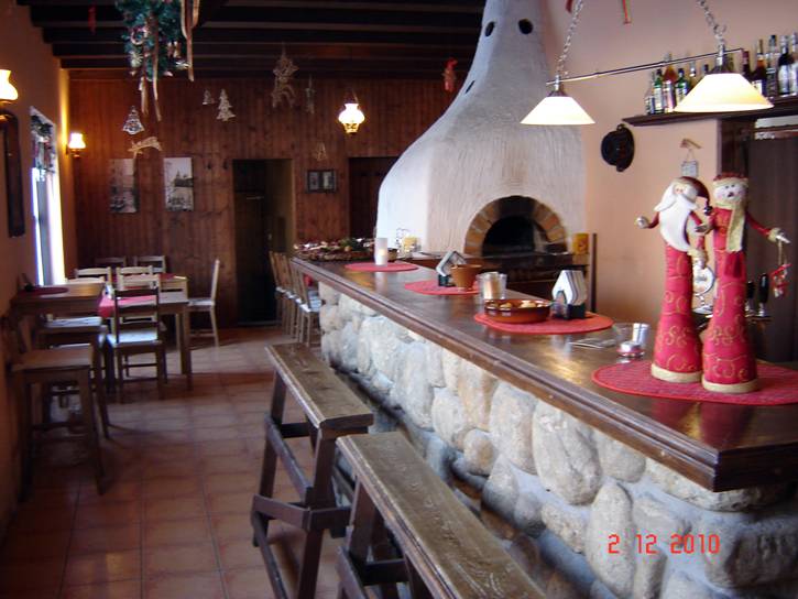 Interiér pizzerie s kamennou pecí a barem